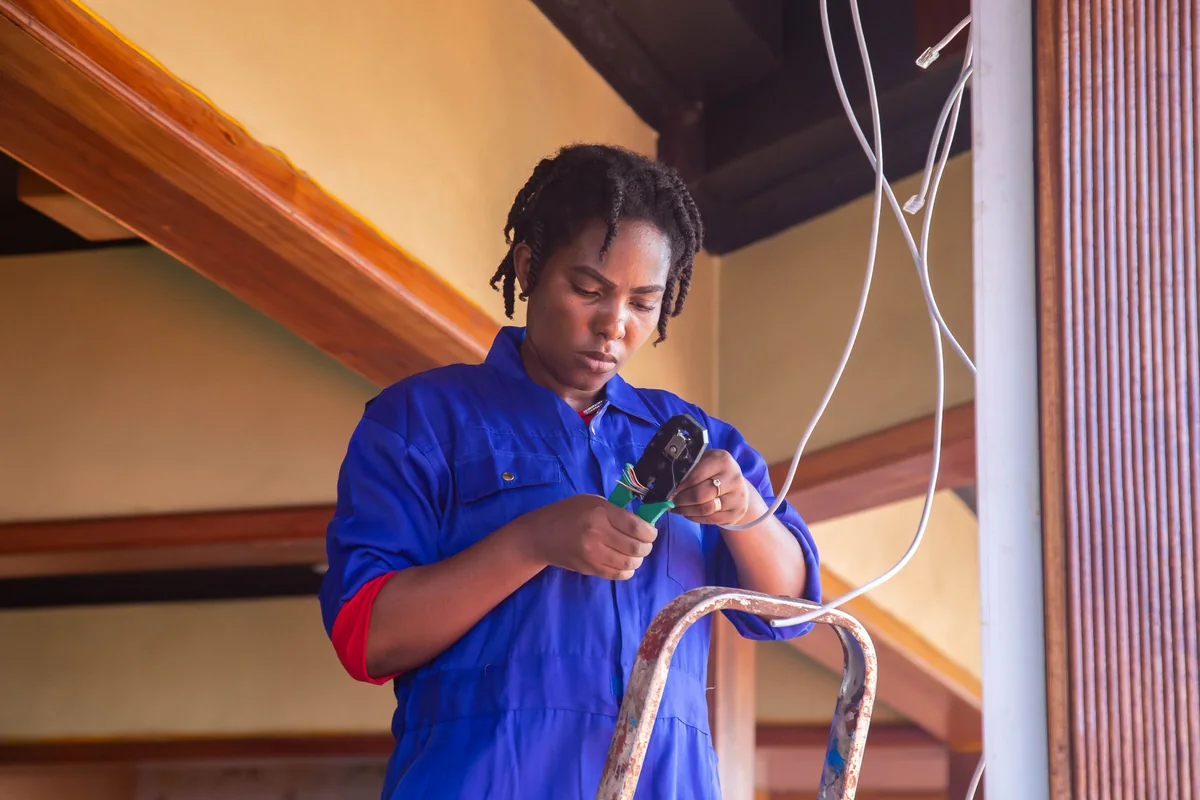 Technician on a ladder preparing cables for an indoor install
